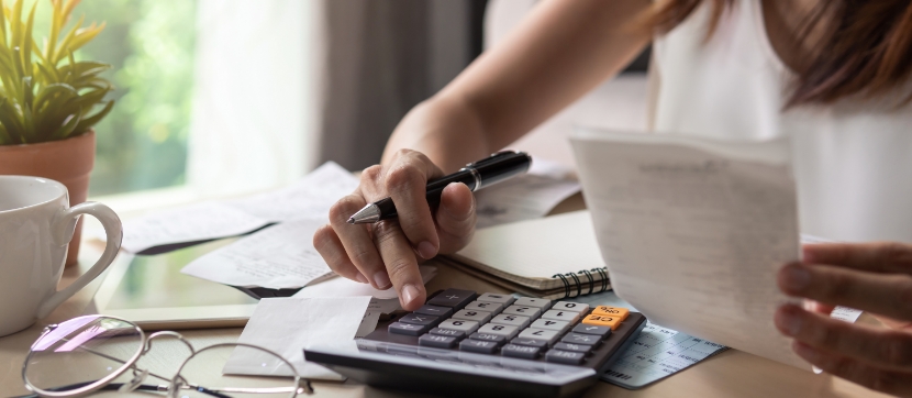 電卓とレシートで支出を確認する女性の手元